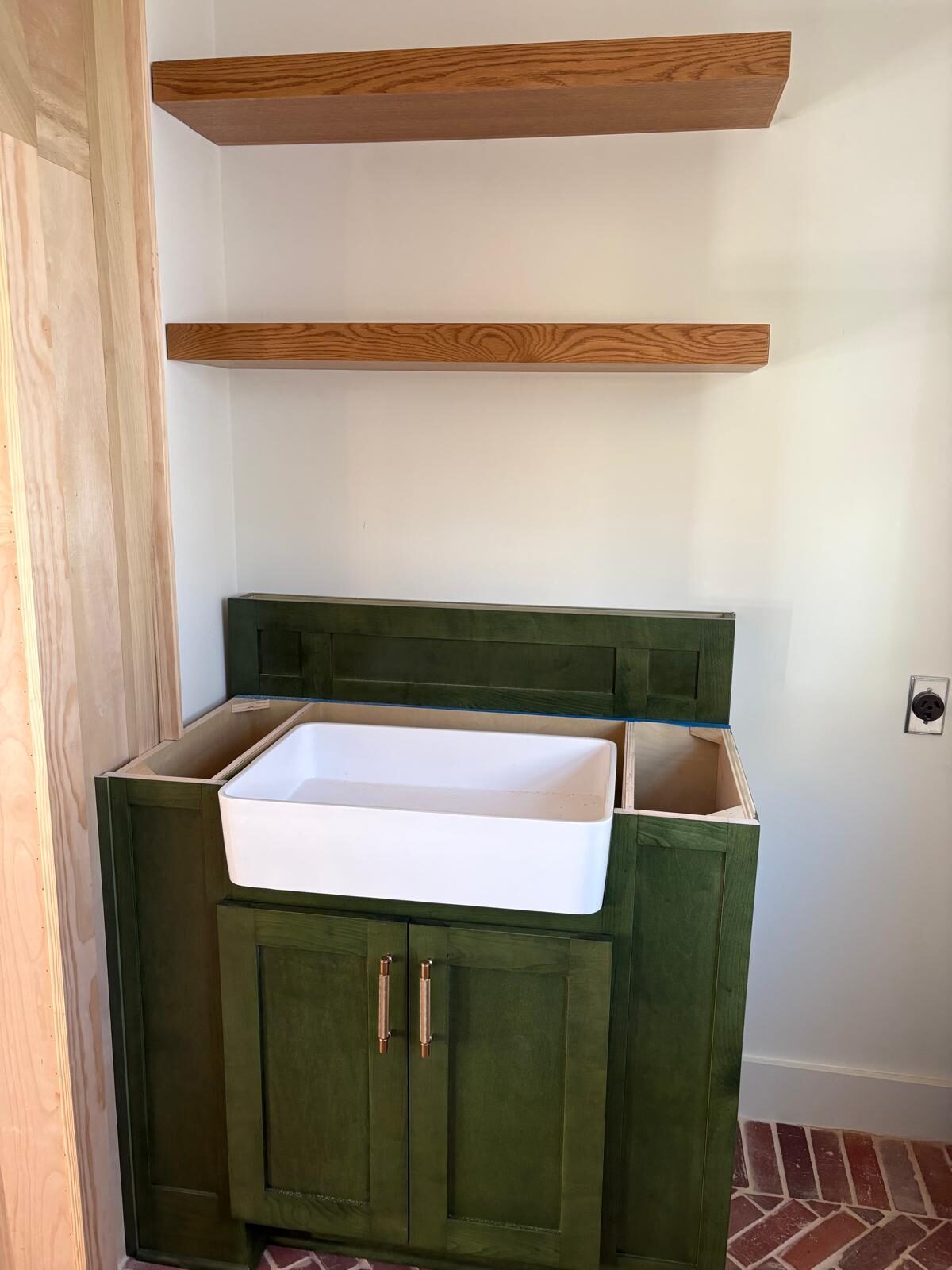 Green vanity with a farmhouse sink and a floating wood shelf