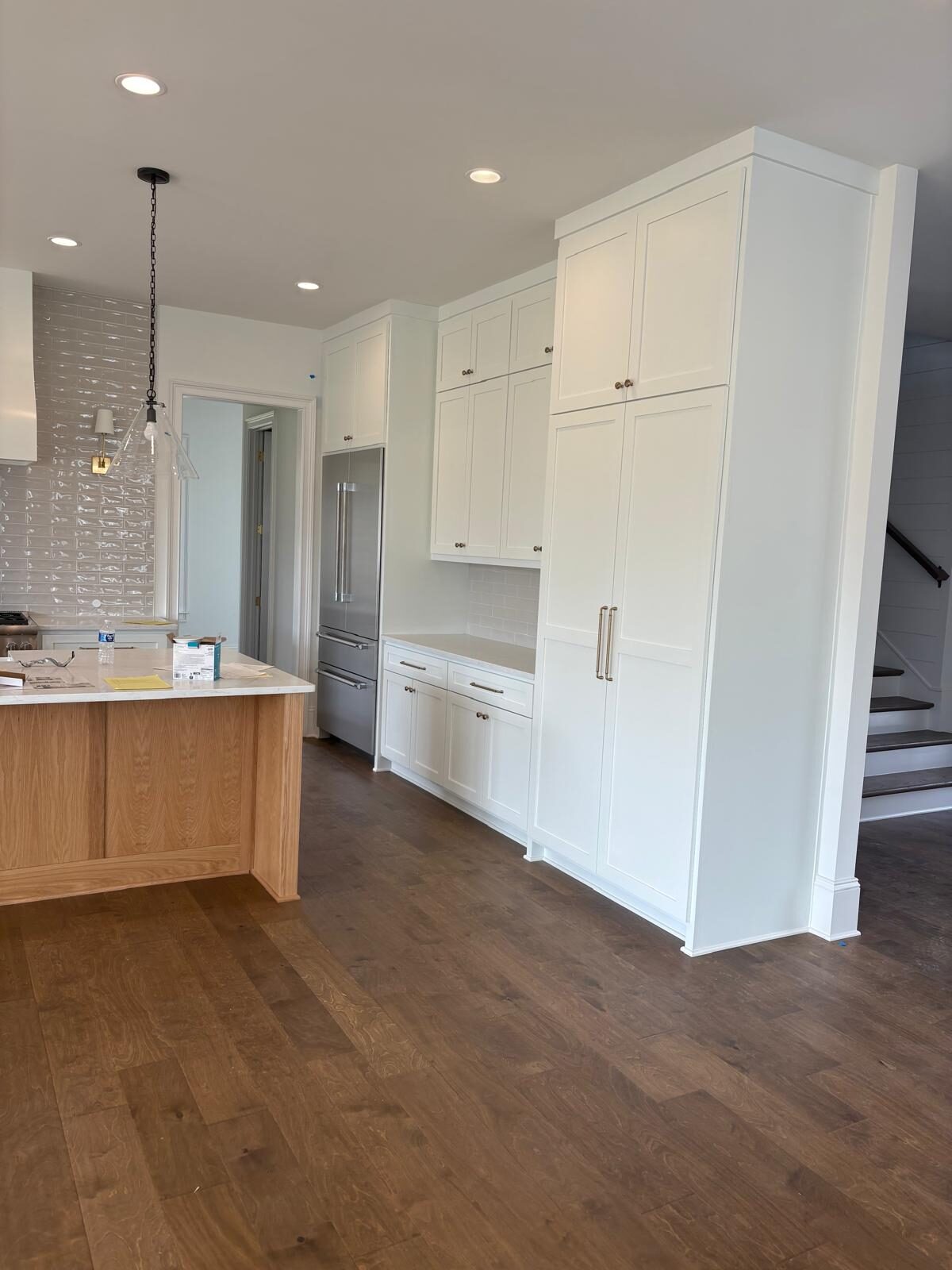 White custom kitchen with an island beside an open staircase
